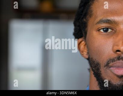 Afroamerikaner, der in der Küche in der Nähe des Kühlschranks steht und ein blaues Hemd trägt, Kopierraum Stockfoto