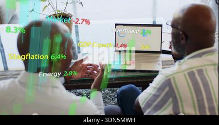 Zwei Kollegen, die sich Karten auf dem Laptop in der Lounge ansehen, tragen ein gestreiftes Hemd mit Überzügen Stockfoto