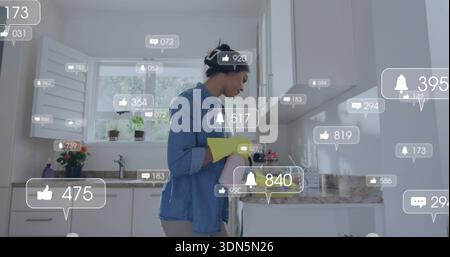 Anlegende Frau mit Denim-Hemd, gelben Handschuhen, die Waschbecken in der Küche reinigen, mit sozialen Ikonen Stockfoto