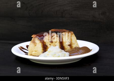 Teller mit Portion Flan mit Karamellcreme und Dulce de leche isoliert auf Schwarz Stockfoto