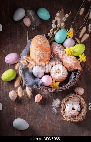 Traditioneller Osterkorb mit bemalten Eiern, Blumen und Brot. Kuchen, Katzetten und Ostereier zu Ostern. Stockfoto