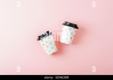 Zwei Kaffeetassen aus Papier mit Deckel auf rosa Hintergrund. Draufsicht, flach. Stockfoto