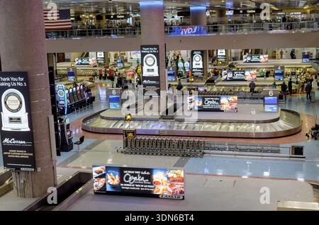 Die Menschen befinden sich an Gepäckkarussells in einem Flughafenterminal, umgeben von Anzeigen, die auf ihr Gepäck in Las Vegas warten Stockfoto