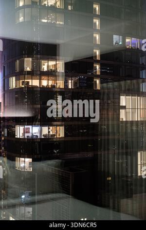 Modernes Hochhaus in NYC in der Abenddämmerung mit leuchtenden Fenstern und urbanen Reflexen in der Glasfassade. Stockfoto
