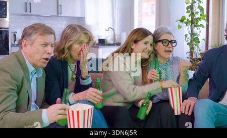 Gruppe von älteren Freunden, die zu Hause mit Begeisterung fernschauen Stockfoto