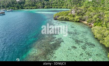 Atemberaubender Blick über die ruhige Bucht in der Nähe des Strawberry Rock Komodo National Park. Die lebendigen türkisfarbenen Untiefen mit Korallengärten sind von einer lebensechten Tafel umgeben Stockfoto