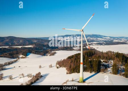 Windenergieanlage, die auf einem verschneiten Winterfeld betrieben wird. Konzept der Energieunabhängigkeit und der nachhaltigen Elektrizität. Stockfoto