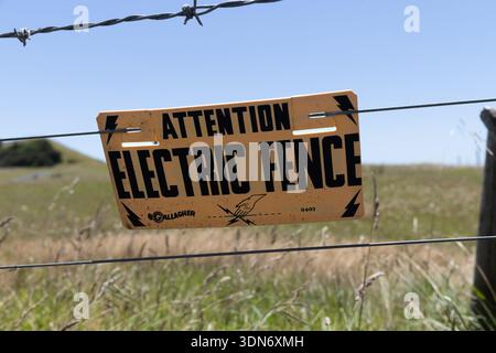 Warnschild für elektrischen Zaun auf ländlichem Ackerland, Coromandel Peninsula, Nordinsel, Neuseeland. Stockfoto