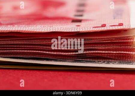 Ein Stapel Papiergeld mit amerikanischem und chinesischem Geld, chinesische Banknoten von 100 Yuan, Nahaufnahme Stockfoto
