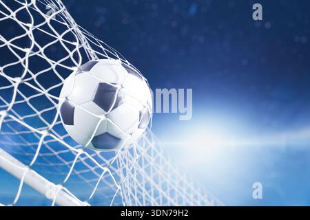 Nahaufnahme eines Fußballballs, der mit einer hellen Linse auf blauem Stadionhintergrund ins Netz schlägt. Konzept von Erfolg, Torwertung und Sieg in einem PR Stockfoto