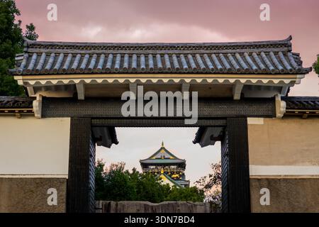 Horizontaler Blick auf das Schloss Osaka bei Sonnenuntergang durch das Haupttor mit rosa Abendhimmel in Japan Stockfoto