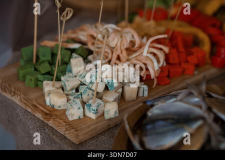 Eine schön gestaltete Wurstplatte mit verschiedenen Käsesorten, Räucherfleisch und lebendigem Gemüse, ideal für Catering, Partys, oder Lebensmittel fotogr Stockfoto