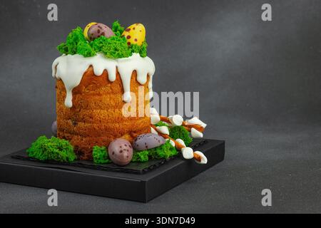 Osterkuchen mit essbarem Moosnest, Schokoladeneiern und handgemachten Weidenzweigen. Traditionelles festliches Dessert mit Hasenfiguren auf schwarzem ston Stockfoto