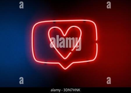 Valentinstag. Neon Heart Social Media Like Icon auf blauem und rotem Hintergrund. Leuchtendes rotes Neonzeichen für eine Herzinfarktblase in sozialen Medien. Die Stockfoto