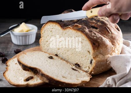 Traditionelles irisches Soda-Brot mit Rosinen, frisch gebacken und in Scheiben geschnitten, serviert auf einem rustikalen Holzbrett mit Butter. Authentisches irisches Essenskonzept, Homema Stockfoto