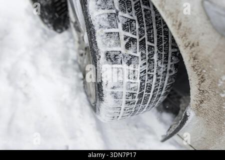 Konzept des Wintertransports und Herausforderungen des Fahrens bei extremen Minusgraden. Nahaufnahme eines dreckigen Autorads mit tiefem Reifenprofil Stockfoto