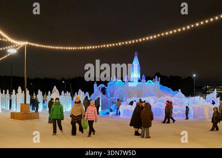 Jekaterinburg, Russland - 5. Januar 2026: Menschenmassen genießen den Winterabend beim Weihnachtsfest. Große, blau beleuchtete Eisrutsche in Form von Schloss, Eis Stockfoto