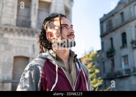 Mann mit Dreadlocks und Bart, der nach draußen blickt und Freiheit an einem sonnigen Tag erlebt Stockfoto