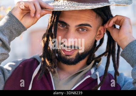 Mann mit Dreadlocks, der Lebensstil und Sommergefühle mit Strohhut erlebt Stockfoto