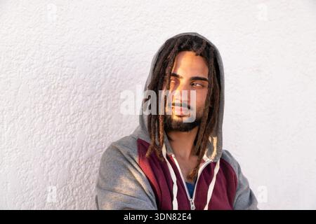 Junger Mann, der den urbanen Lebensstil genießt, einen Hoodie trägt und seine Dreadlocks schützt Stockfoto
