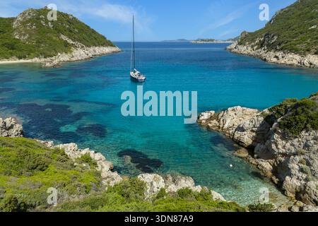 Wunderschöner Blick aus der Vogelperspektive auf die Insel Korfu. Blick auf die Bucht von Porto Timoni, Segelboot auf türkisblauem Wasser und Felsen mit üppiger Vegetation. Euro Stockfoto
