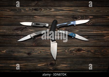 Moderne Klappmesser und eine feste Klinge auf dunklem Holzhintergrund. Stockfoto