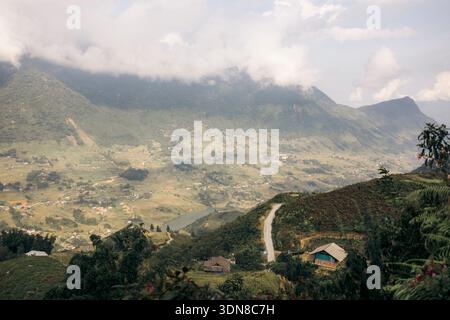 Sanfte Hügel und Wolken über einer malerischen Dorflandschaft mit weit entfernten Bergen. Sapa, Vietnam Stockfoto