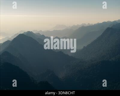 Nebelgebirge mit sanftem Morgenlicht und mehrschichtigen Gipfeln, die sich bis in die Ferne erstrecken. Yen Thuy District, Hoa Binh, Vietnam Stockfoto