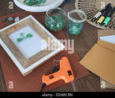 Meeresglas im Rahmen. Kunst aus natürlichen Materialien herstellen. Klebepistole und Treibholz für Bilder. Hobbys und Kreativität. Wiederverwendung und Natur, Ökologie. Stockfoto