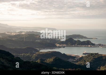 Küstenlandschaft mit Bergen, Wasser und verstreuten Wolken unter einem sanften Sonnenaufgang. Jioufen, Bezirk Ruifang. New Taipei City, Taiwan Stockfoto