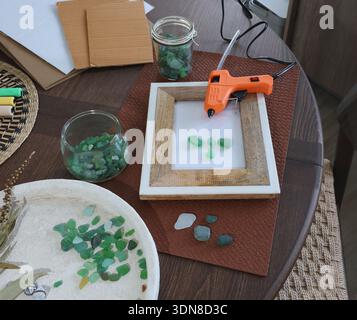 Meeresglas im Rahmen. Kunst aus natürlichen Materialien herstellen. Klebepistole und Treibholz für Bilder. Hobbys und Kreativität. Wiederverwendung und Natur, Ökologie. Stockfoto