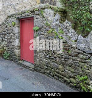 Historische Holztür in einer verwitterten Kalksteinmauer. Stockfoto