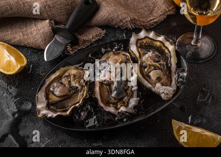 Frische Austern aus nächster Nähe auf Eis serviert mit Zitrone und Wein. Gesunde Meeresfrüchte, Gourmetgerichte. Stockfoto