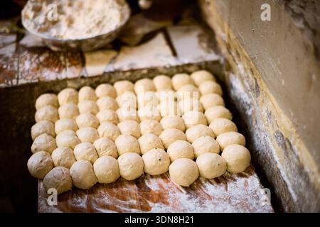 Teigkugeln, die ordentlich auf einer mit Mehl bestaubten Holzoberfläche angeordnet sind, sind bereit zum Backen. Kigali, Ruanda Stockfoto
