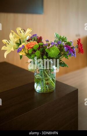 Lebendiger Blumenstrauß in einer Glasvase auf einer Holzoberfläche drinnen. Belgien Stockfoto