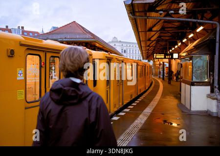 Person, die am Bahnsteig steht und am Abend den gelben Zug am Stadtbahnhof beobachtet. Deutschland Stockfoto