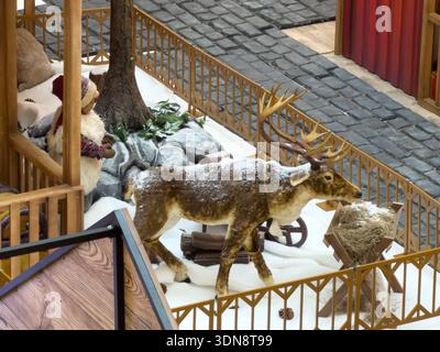 Blick von oben auf eine detailreiche Rentier- und Zwergpuppe, umgeben von künstlichem Schnee, Felsen und Bäumen, die ein magisches Weihnachtswinterwunderland darstellt Stockfoto