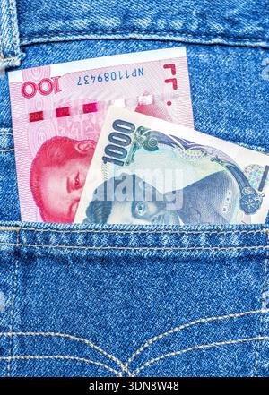 Chinesische Yuan- und japanische Yen-Banknoten ragen aus der hinteren Jeanstasche Stockfoto