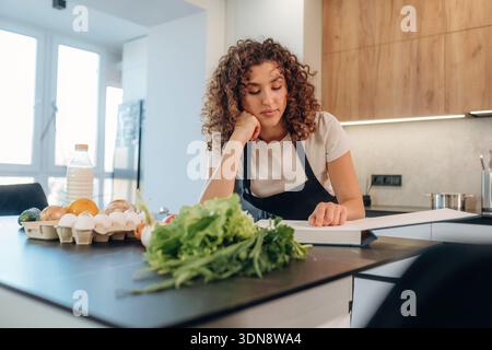Attraktive Frau, die frisches Gemüse auf der Küchenzeile während des Kochens zubereitete. Stockfoto