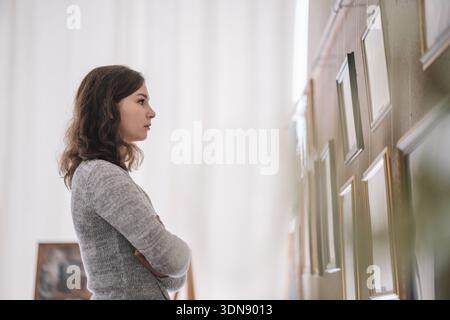 Mitten in der Aufnahme einer jungen weißen schönen Frau in einem eleganten Anzug ist in einer Kunstgalerie und benutzt ihr Smartphone mit Online-Ausflug. Modernes Kulturhaus Stockfoto