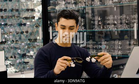 Männlicher Kunde, der Brillengestell im Optikgeschäft untersucht Stockfoto