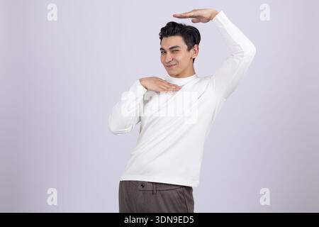 Junger Mann posiert mit Händen hinter dem Kopf im Studio Stockfoto