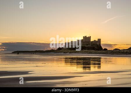 Das berühmte Bamburgh Castle an einem eiskalten Morgen bei Sonnenaufgang, neben dem schneebedeckten Strand in Northumberland, England. Stockfoto