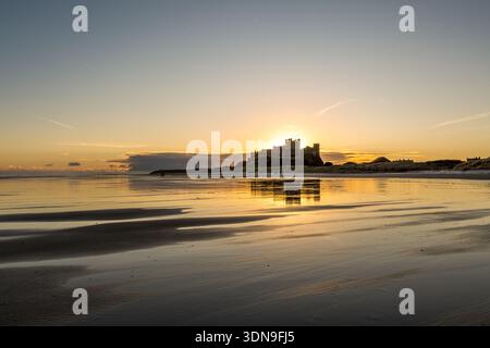 Das berühmte Bamburgh Castle an einem eiskalten Morgen bei Sonnenaufgang, neben dem schneebedeckten Strand in Northumberland, England. Stockfoto