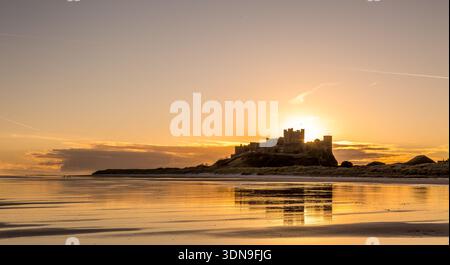 Das berühmte Bamburgh Castle an einem eiskalten Morgen bei Sonnenaufgang, neben dem schneebedeckten Strand in Northumberland, England. Stockfoto