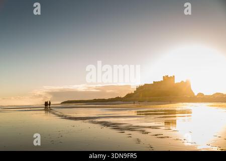 Das berühmte Bamburgh Castle an einem eiskalten Morgen bei Sonnenaufgang, neben dem schneebedeckten Strand in Northumberland, England. Stockfoto