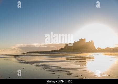 Das berühmte Bamburgh Castle an einem eiskalten Morgen bei Sonnenaufgang, neben dem schneebedeckten Strand in Northumberland, England. Stockfoto