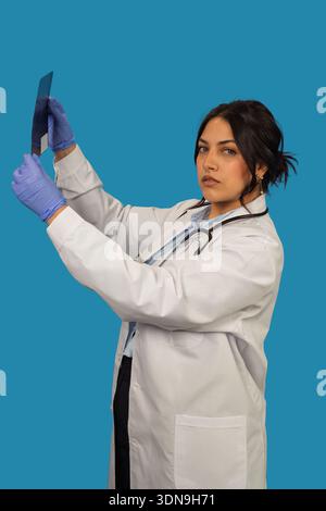 Ärztin im Laborkittel und Handschuhen bei der Untersuchung eines medizinischen Scans Stockfoto