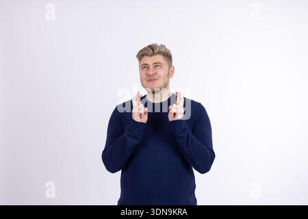 Der Typ, der die Finger drückt, um Glück auf weißem Hintergrund zu haben Stockfoto