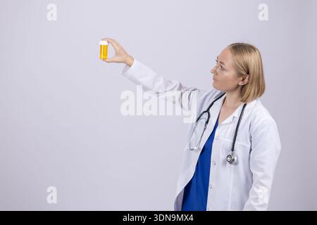 Eine Ärztin, die sich eine medizinische Glasflasche im Studio ansieht Stockfoto